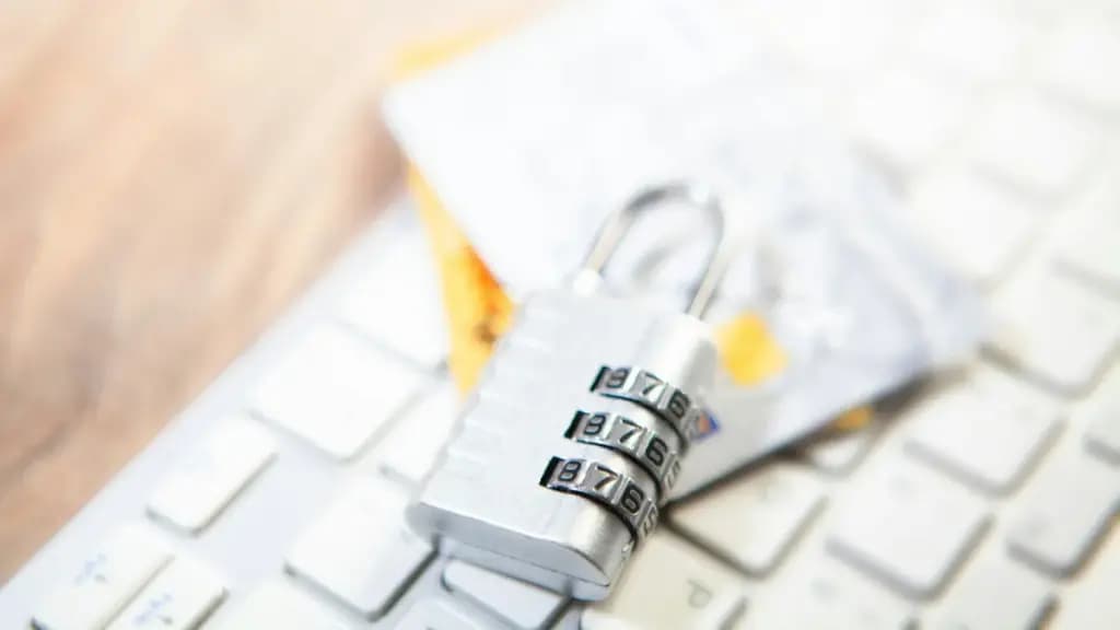 Combination padlock on a computer keyboard beside payment cards.