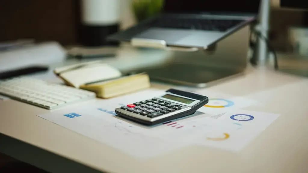 Calculator and laptop on a desk for financial work.