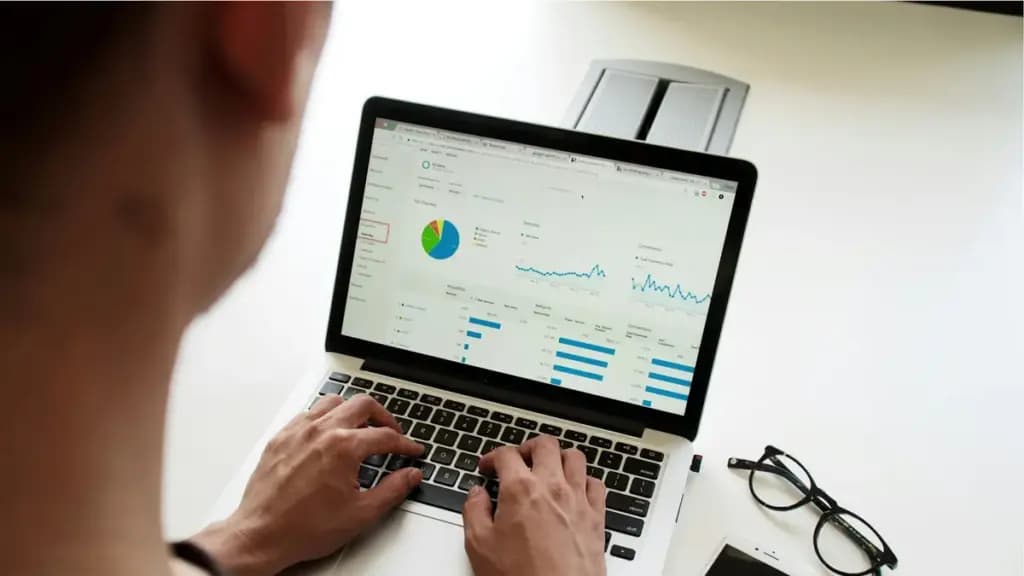 Person working with charts and a business planning board on a laptop.