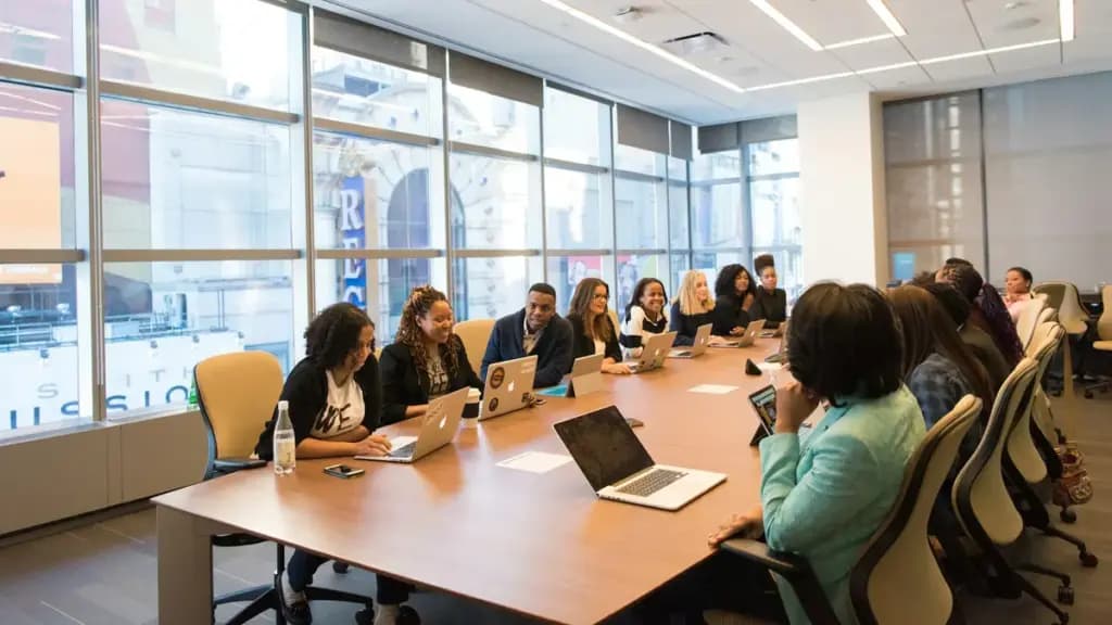 Colleagues working together around a meeting table with laptops.